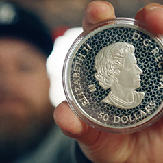 50 dollar coin being held close to camera by collector who is out of focus