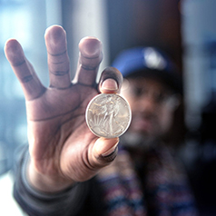 Collector holding single coin in fingers close to camera